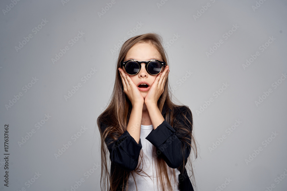1723570 stylish girl surprised with glasses holds hands on face on gray background portraits