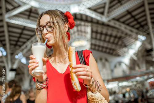 Woman with Horchata, traditional spanish drink made from almonds, standing in the Central foodmarket of Valencia city photo