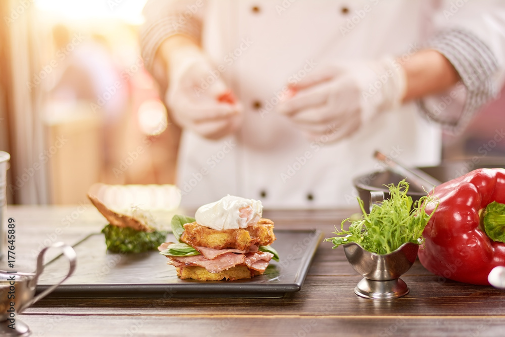 Chef cooking benedict in restaurant. Delicious benedict, fresh vegetables, blurrred background. Chef cooking benedict in restaurant. Delicious benedict, fresh vegetables, blurrred background.