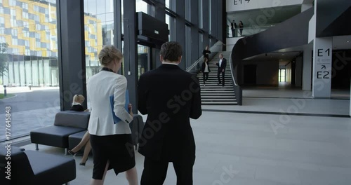 Modern business people walking in glass hall of office building