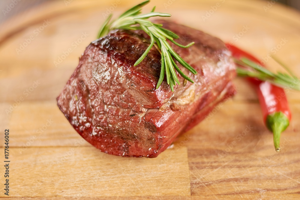 Appetizing grilled beef steak. Beef steak medium grilled with rosemary and red chili pepper. Delicious food on wooden background. Appetizing grilled beef steak. Beef steak medium grilled with rosemary and red chili pepper. Delicious food on wooden background.