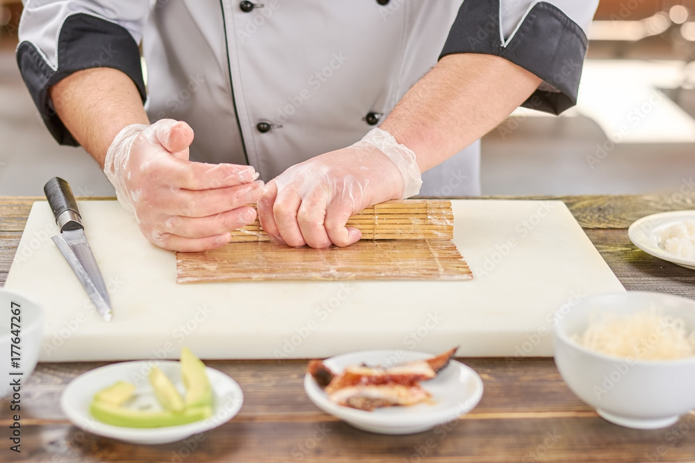 Chef hands shaping sushi roll. Male cook hands making japanese sushi roll with bamboo mat. Chef at work, kitchen. Chef hands shaping sushi roll. Male cook hands making japanese sushi roll with bamboo mat. Chef at work, kitchen.