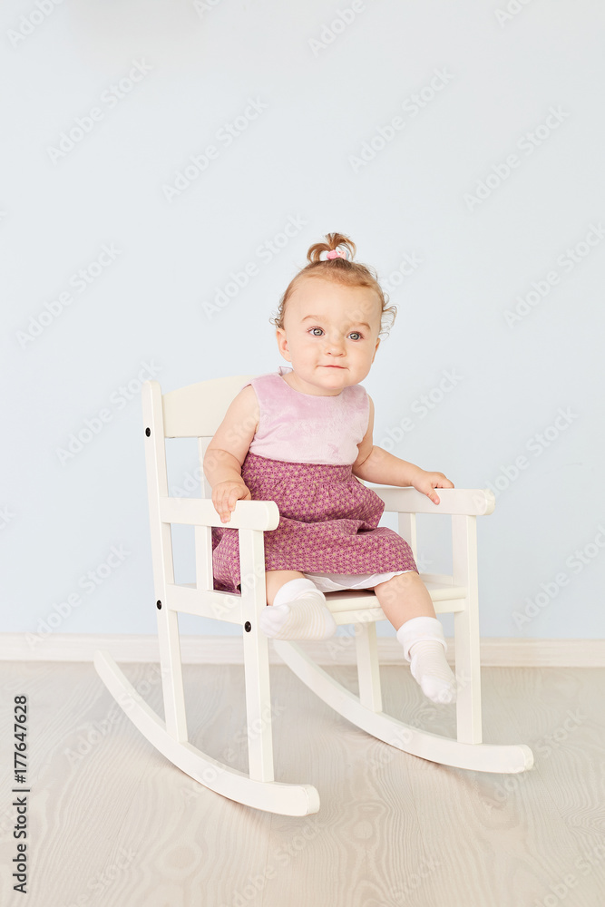 Fashionable little cute girl sitting thoughtful on the white chair posing looking away Fashionable little cute girl sitting thoughtful on the white chair posing looking away