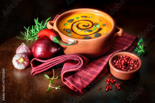 Pumpkin creme soup served in pottery bowl with thyme leaves and pumpkin seeds photo