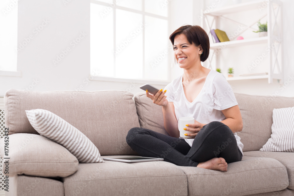 Smiling girl at home chatting online on smartphone and drinking coffee Smiling girl at home chatting online on smartphone and drinking coffee