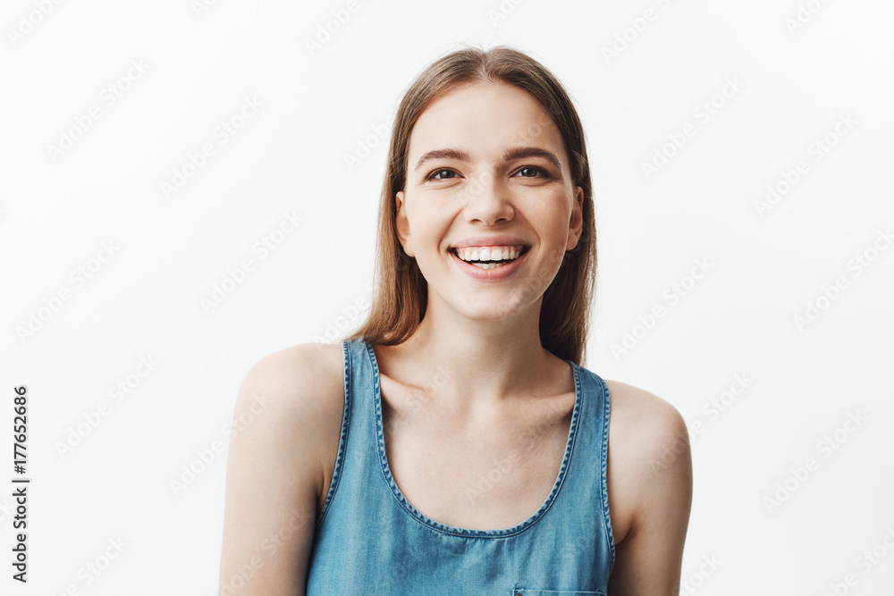 Beautiful young european young woman with dark hair and stylish hairstyle in blue shirt laughing out loud in funny joke, looking in camera with happy and calm face expression. Positive emotions. Beautiful young european young woman with dark hair and stylish hairstyle in blue shirt laughing out loud in funny joke, looking in camera with happy and calm face expression. Positive emotions.