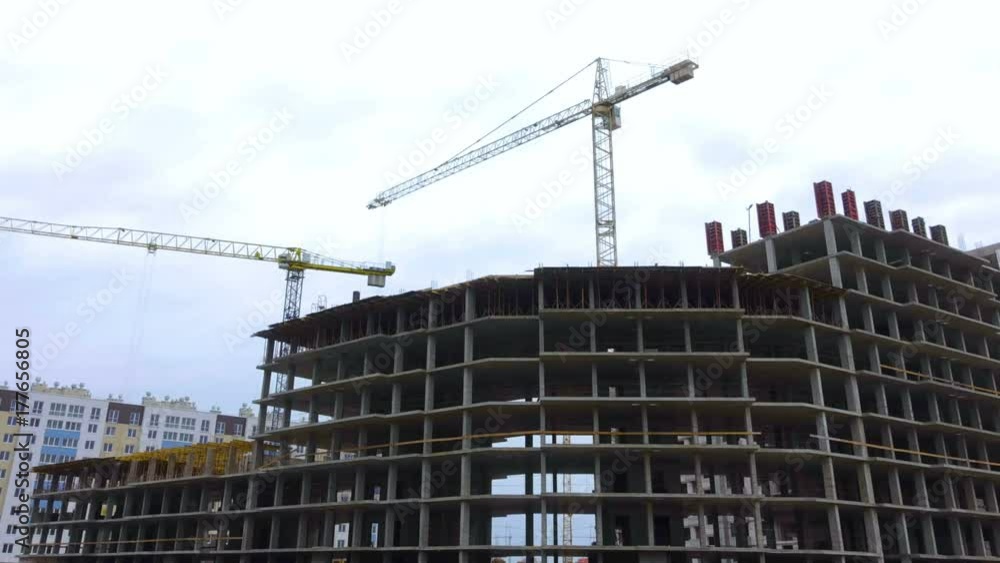Construction site with workers of high-rise houses of brick tower cranes. Time Lapse. Construction crane works on construction site, will raise bricks, concrete slabs.