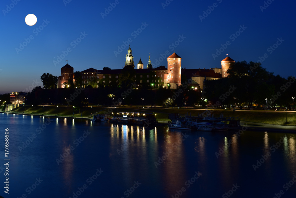 View of Wawel Castle and Vistula River under moonlight at night time in Krakow, Poland