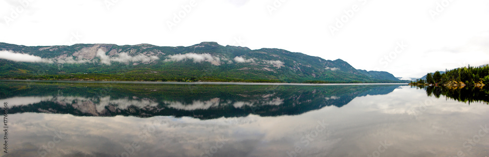 View of a fjord in calm misty morning with low clouds
