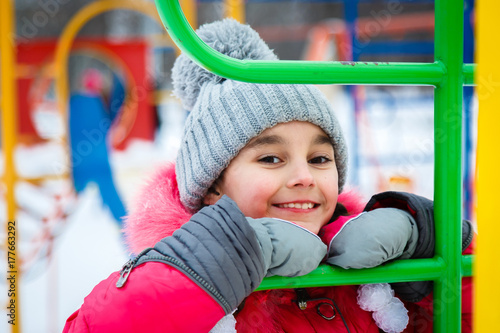 Happy girl playing on a  playground at winter frosty day.
