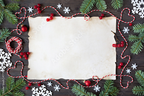 Christmas wooden background with paper, snowflakes, branches tree, red berries and twine in the form of hearts