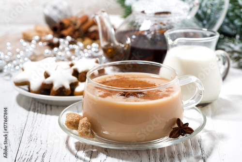 cup of spicy masala tea and Christmas cookies on white background