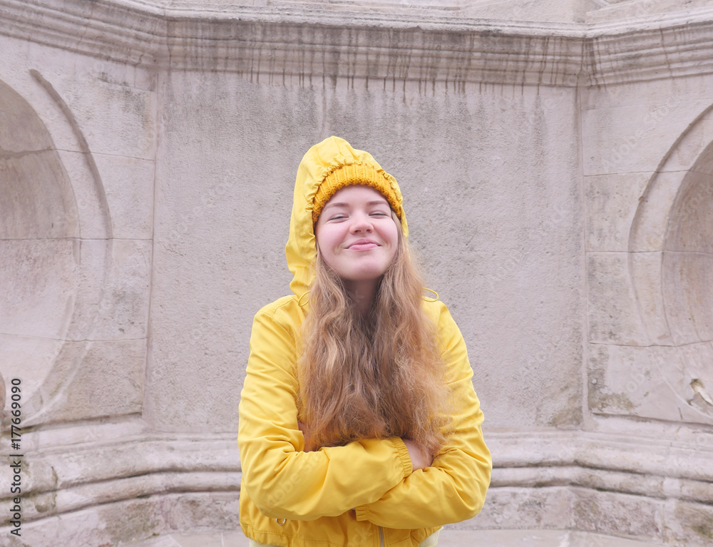 Girl wearing yellow clothes posing to the camera and showing different emotions. Hipster girl in yellow jacket, hat standing outdoors. Pretty girl standing behind the street background. Hat commercial