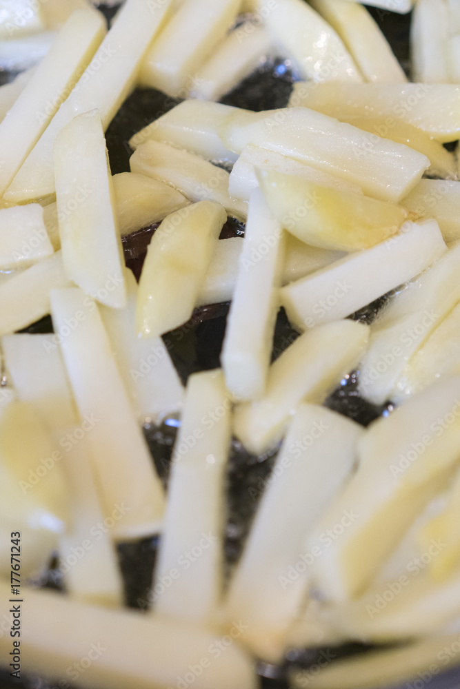 Frying rounded potatoes on a black pan with boiling oil. Frying rounded potatoes on a black pan with boiling oil.