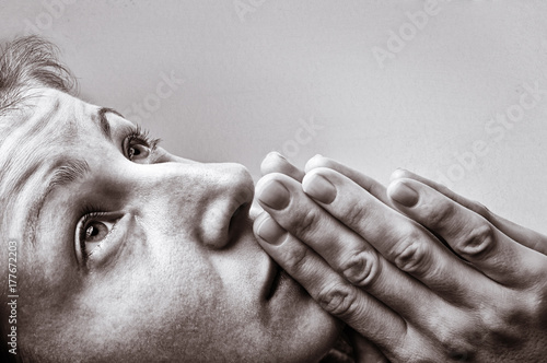 Dramatic, black and white image of a woman during a prayer on light background. 