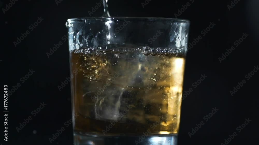 Alcohol is poured to the glass with ice cubes in slow motion, barman makes drinks, 240 frames per second Alcohol is poured to the glass with ice cubes in slow motion, barman makes drinks, 240 frames per second