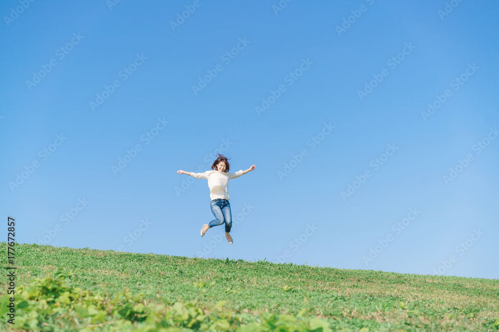 ジャンプする女性・青空