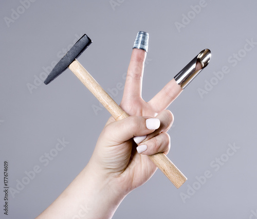 Hand Holding a Small Hammer with Two Thimbles.