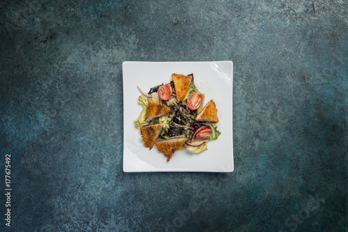 Pan-Asian salad, vegetables with fried chicken. On a square white plate. Top view photo