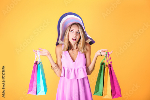 Beautiful woman with paper bags on yellow background