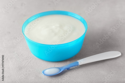 Spoon and bowl with baby porridge on table
