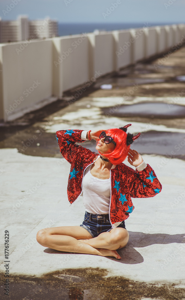 Beautiful girl devil sitting on city background near the puddle with his  reflection. In anticipation of Halloween. Portrait. Wears black sunglasses  foto de Stock | Adobe Stock