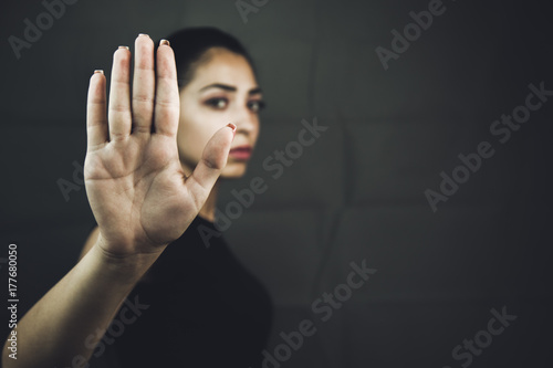 Serious woman gesturing to stop isolated on a black background