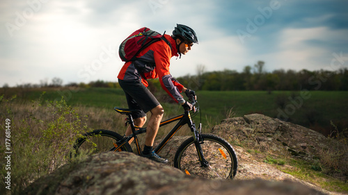 Cyclist in Red Riding Bike on the Rocky Trail at Evening. Extreme Sport and Enduro Biking Concept.