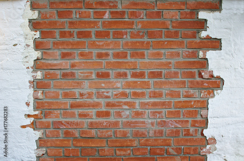 Red brick wall partly plastered with white plaster