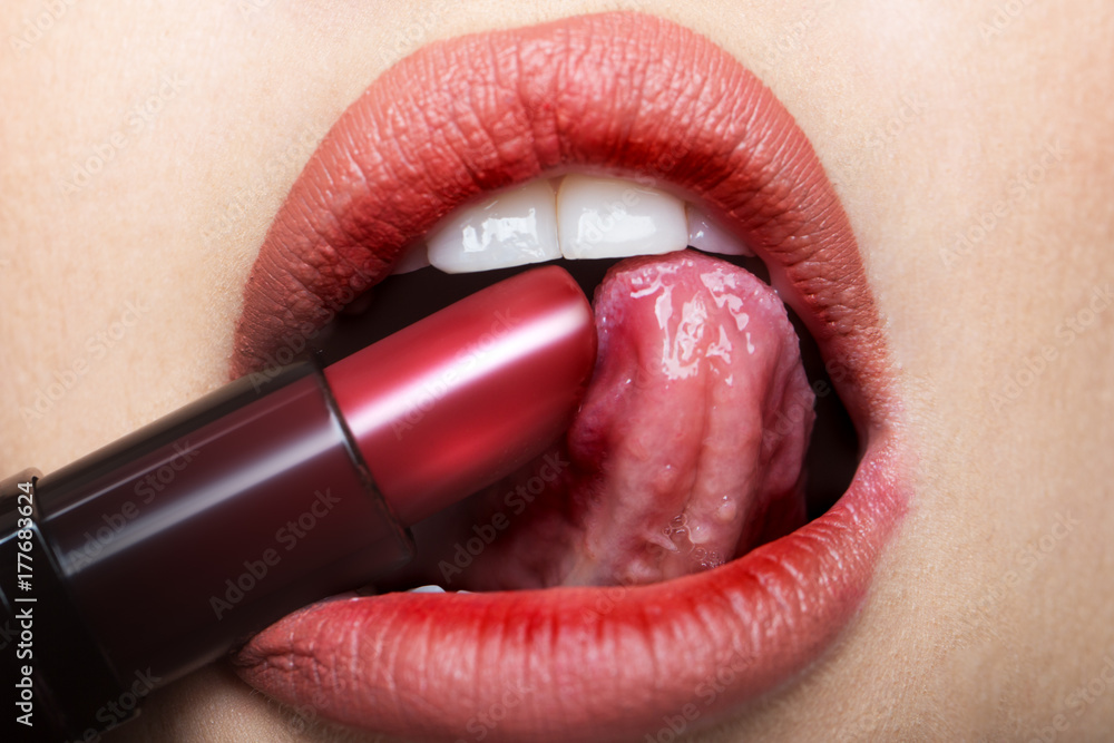 Lipstick, sexy tongue in female mouth. Red lips and open sensual mouth from girl or woman. Exciting for beautiful beauty. Closeup cosmetic products. Cosmetics concept or oral sex Stock Photo