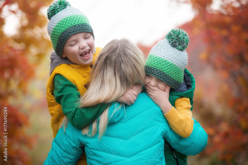 Obraz premium Two little boys gently hug his mother.A walk in the autumn woods.