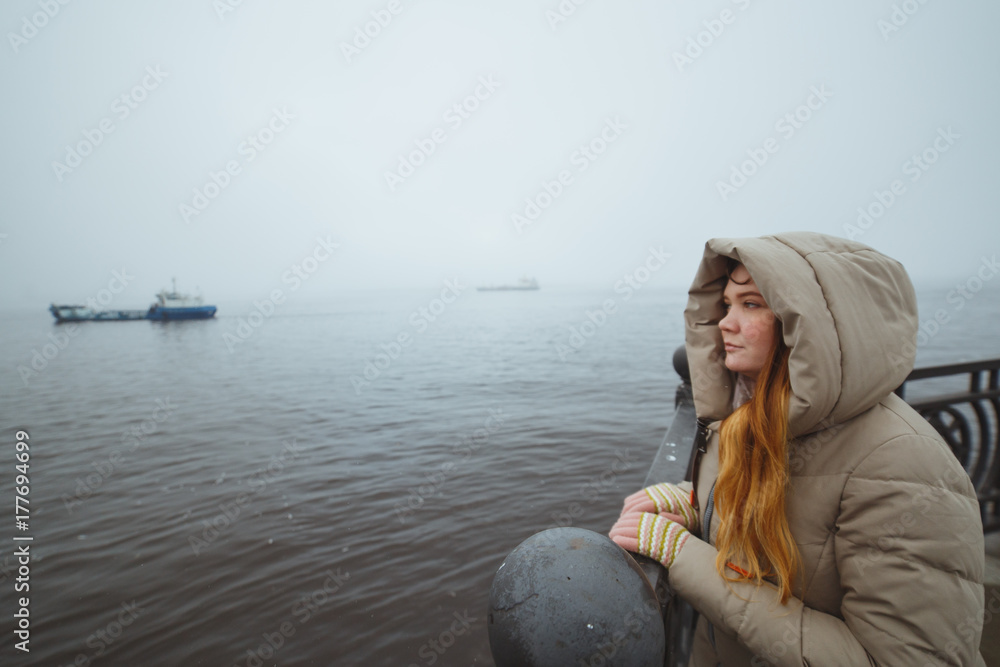 Woman standing alone at sea coast and looking on ship. Winter time. Seaman's wife Woman standing alone at sea coast and looking on ship. Winter time. Seaman's wife