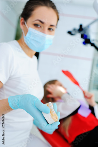 Dentist on the background of the patient holds a ceramic imprint of the jaw in his hands