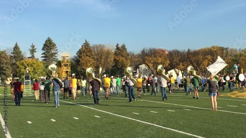 A marching band rehearses for event a day before in bright sunlight.  