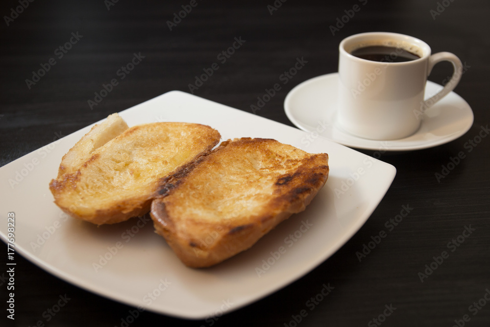 French bread toasted with butter on the plate with coffee. Pao na chapa traditional brazilian breakfast. Overview French bread toasted with butter on the plate with coffee. Pao na chapa traditional brazilian breakfast. Overview