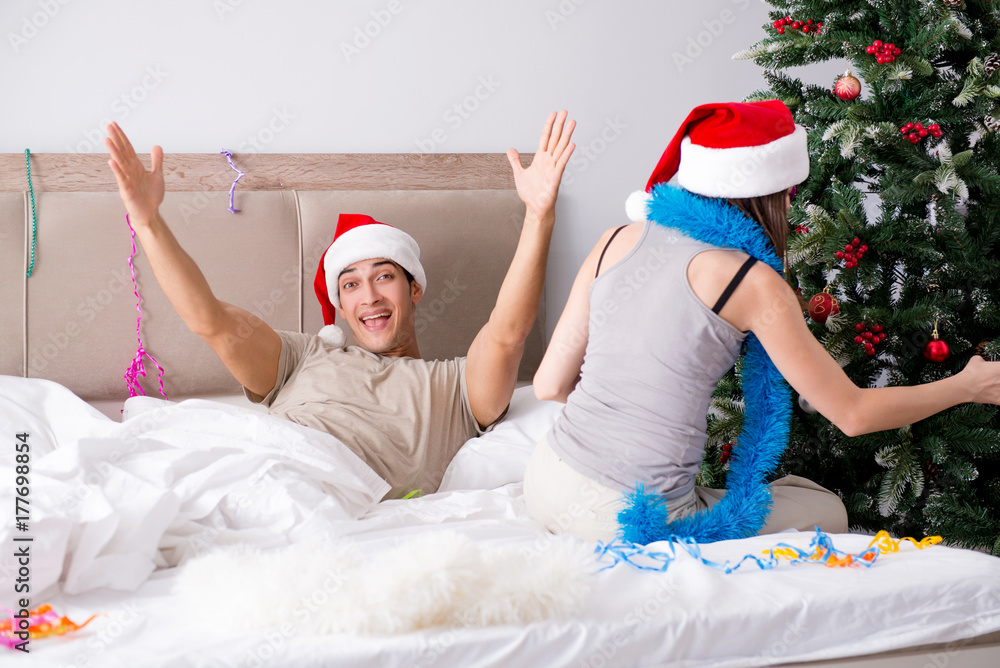 Obraz premium Young happy family celebrating christmas in bed