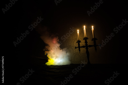 burning old candle vintage wooden candlestick. on dark toned foggy Background.
