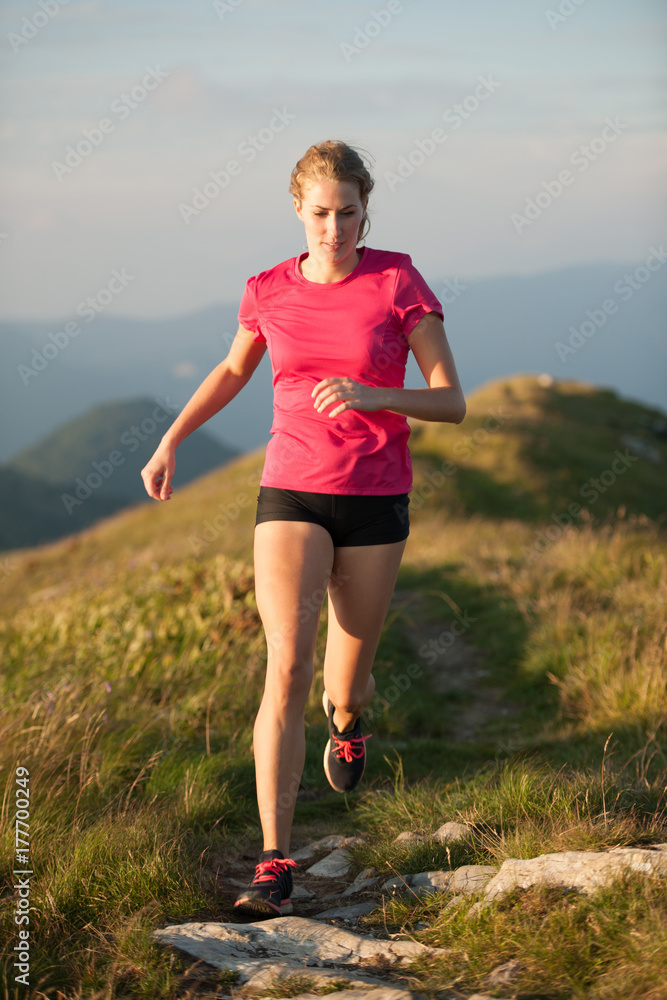 Woman runs on a top of the mountains with mountain range in background Woman runs on a top of the mountains with mountain range in background