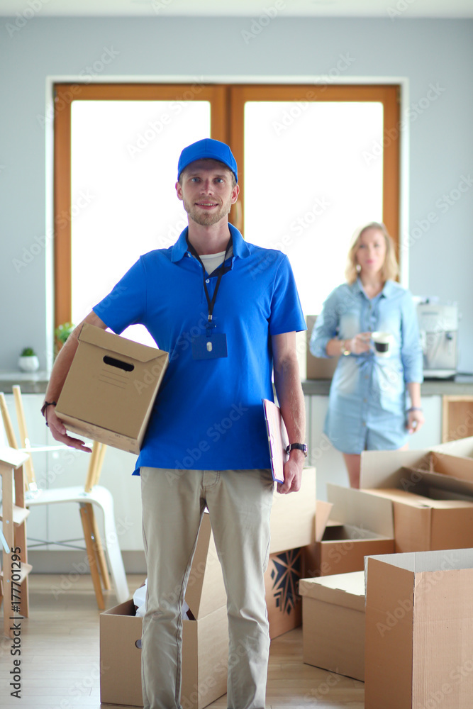 Smiling delivery man in blue uniform delivering parcel box to recipient - courier service concept. Smiling delivery man in blue uniform Smiling delivery man in blue uniform delivering parcel box to recipient - courier service concept. Smiling delivery man in blue uniform