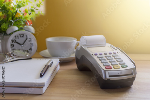 Credit Card Terminal or EDC on cashier wooden table in the store with calculator, clock,credit cards and laptop on wooden / technology and market concept photo