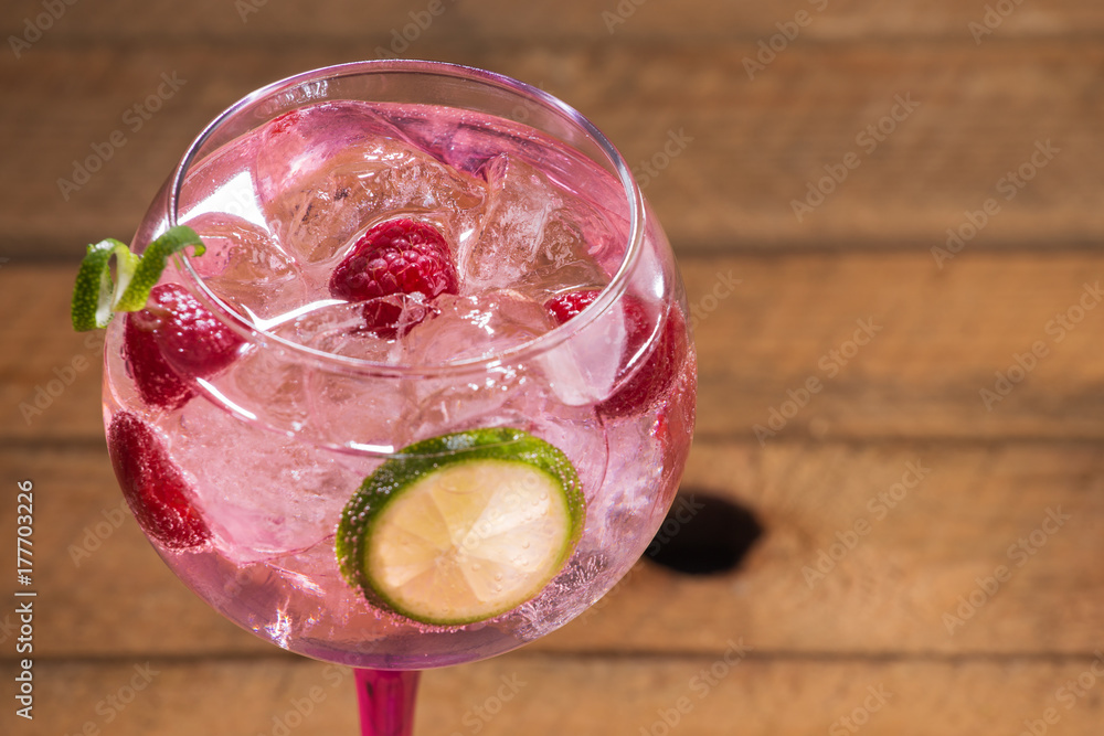 Pink tonic gin with raspberries, wooden background