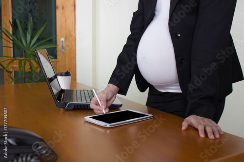 working  pregnant, pregnant woman with tablet on wood table.