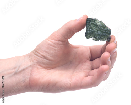 Woman's hand holding Moldavite (form of tektite found along the banks of the river Moldau in Czech republic) isolated on white background photo