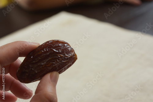 close up fingers holding dried date fruit on table photo