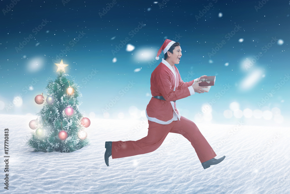 Running asian man wearing santa claus costume holding gift