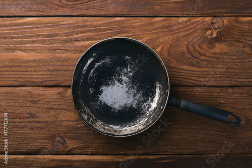 Frying pan. On a wooden black background. Top view. Free space for your text.