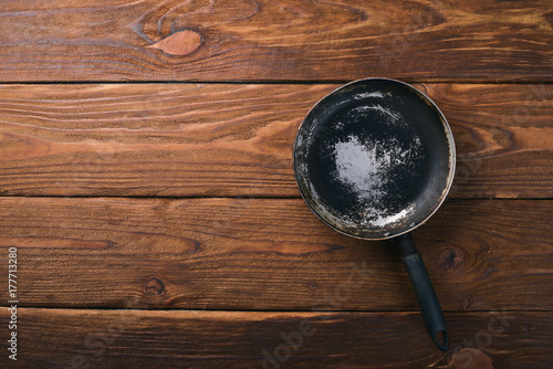 Frying pan. On a wooden black background. Top view. Free space for your text.