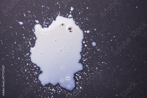 White milk spilled and splash on the dark floor surface. photo