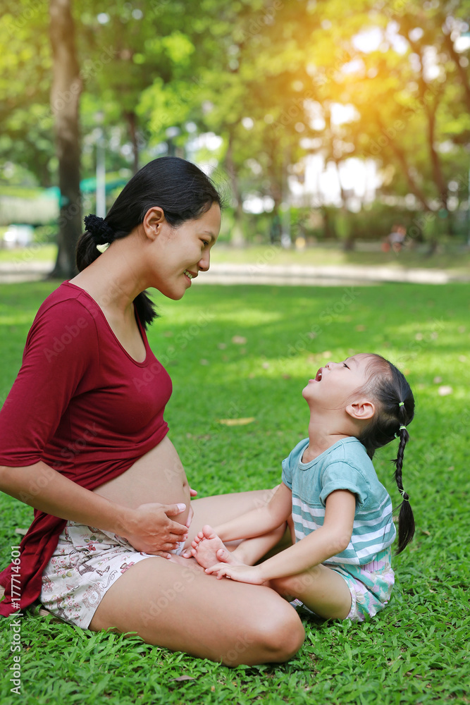 Little girl with her pregnant mother in the park.