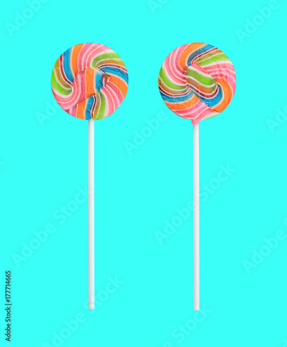 Rainbow lollipop swirl on stick isolated on sweet pastel color background. © zilvergolf